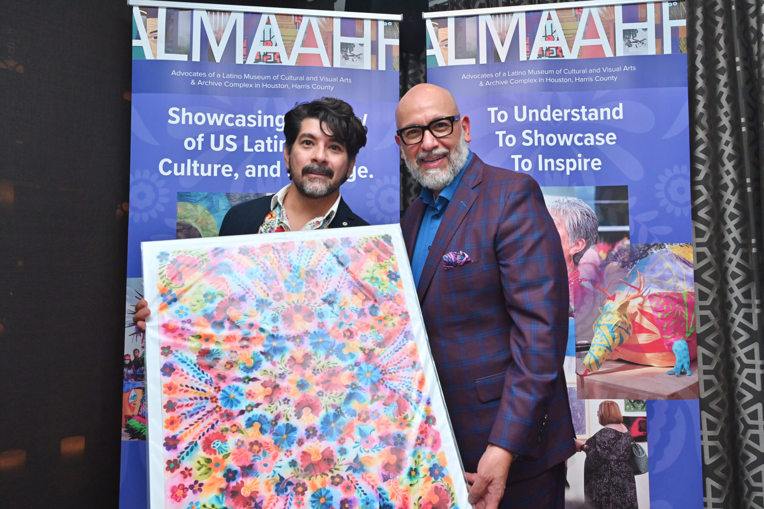 Two ALMAAHH supporters holding colorful artwork at an ALMAAHH gala event