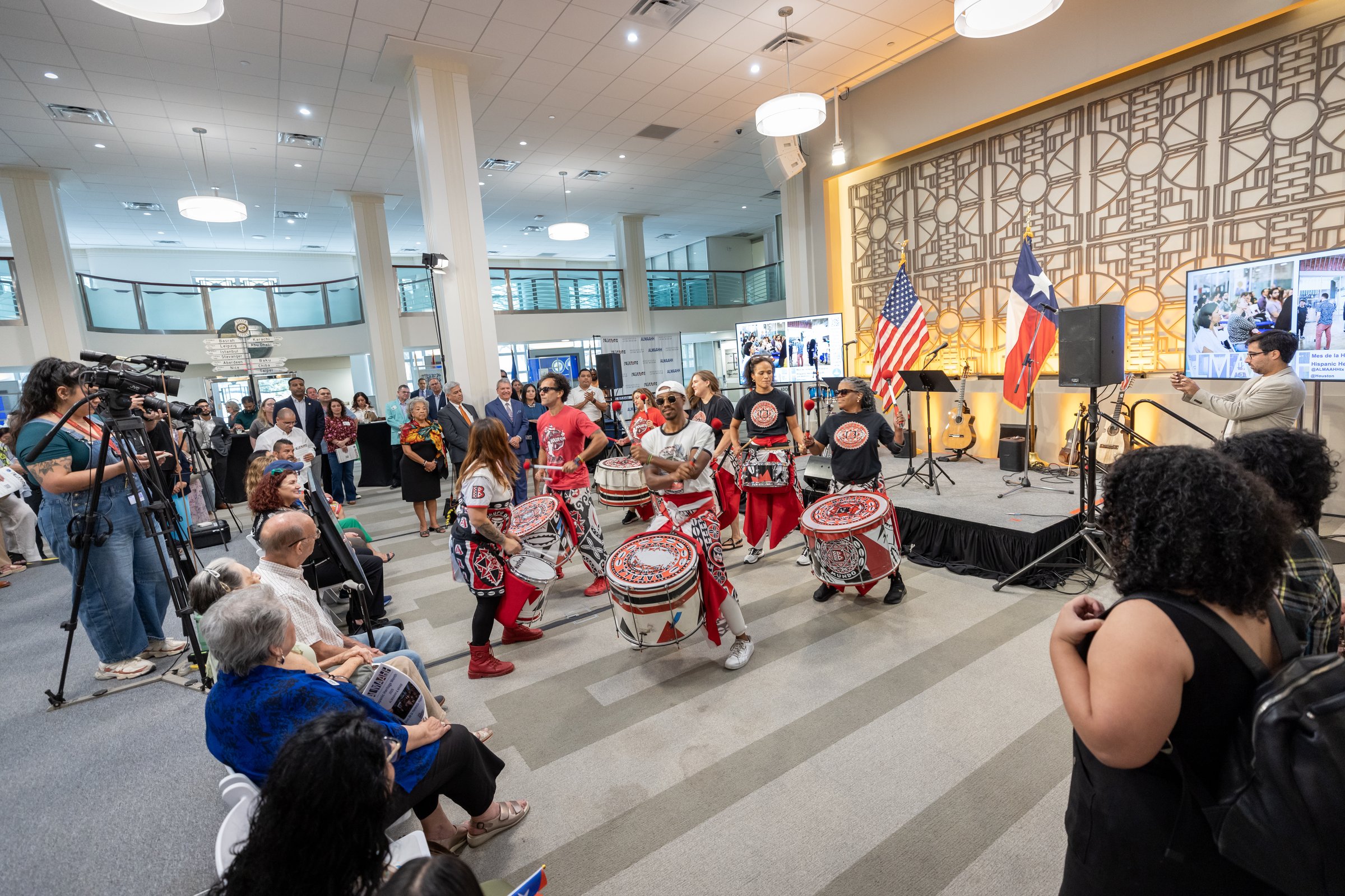 Batalá Houston percussion ensemble performing at Houston City Hall, 2025 — audience and flags visible in the crowd